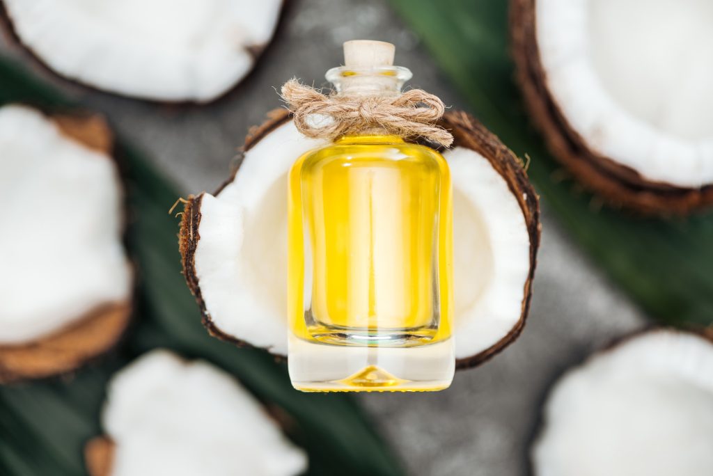 Selective focus of coconut oil in bottle on white coconut half