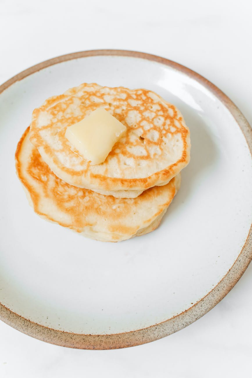 photo of pancakes with butter on white ceramic plate