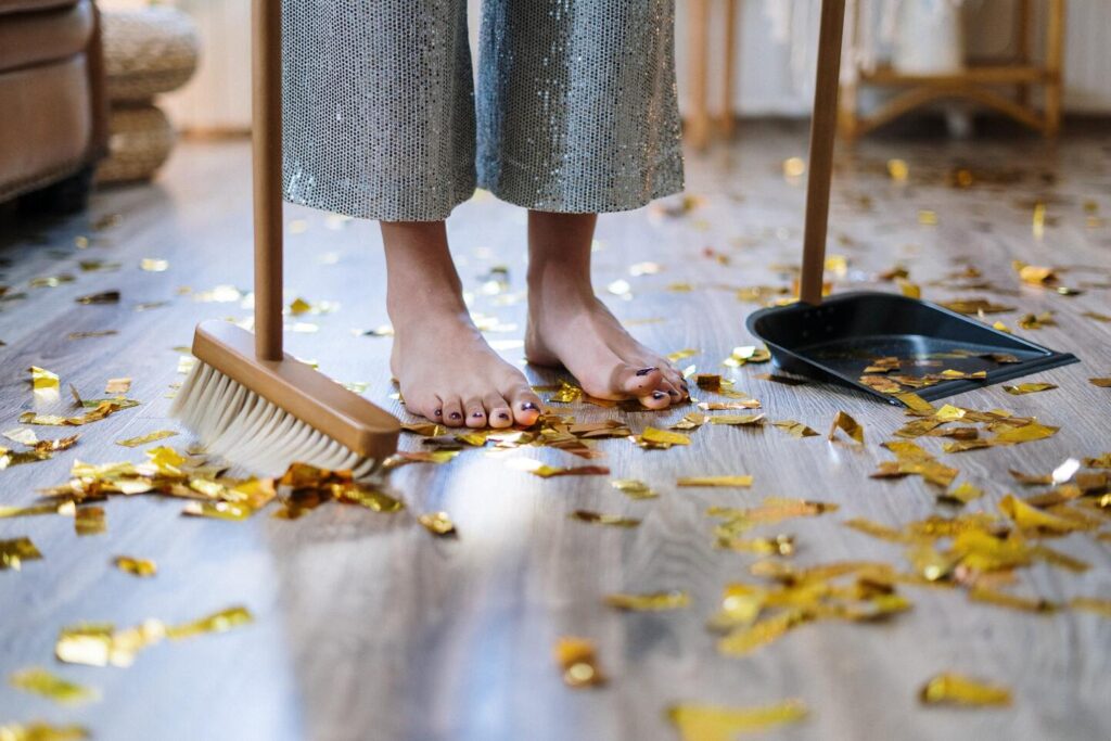 Woman cleaning up fall leaves with broom and dustpan